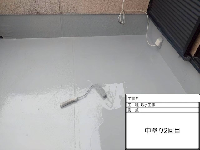 ウレタン防水材の2層目（中塗り2回目）の塗布作業。既定の塗膜厚を確保し、耐久性を高めるために重ね塗りを行っている様子。